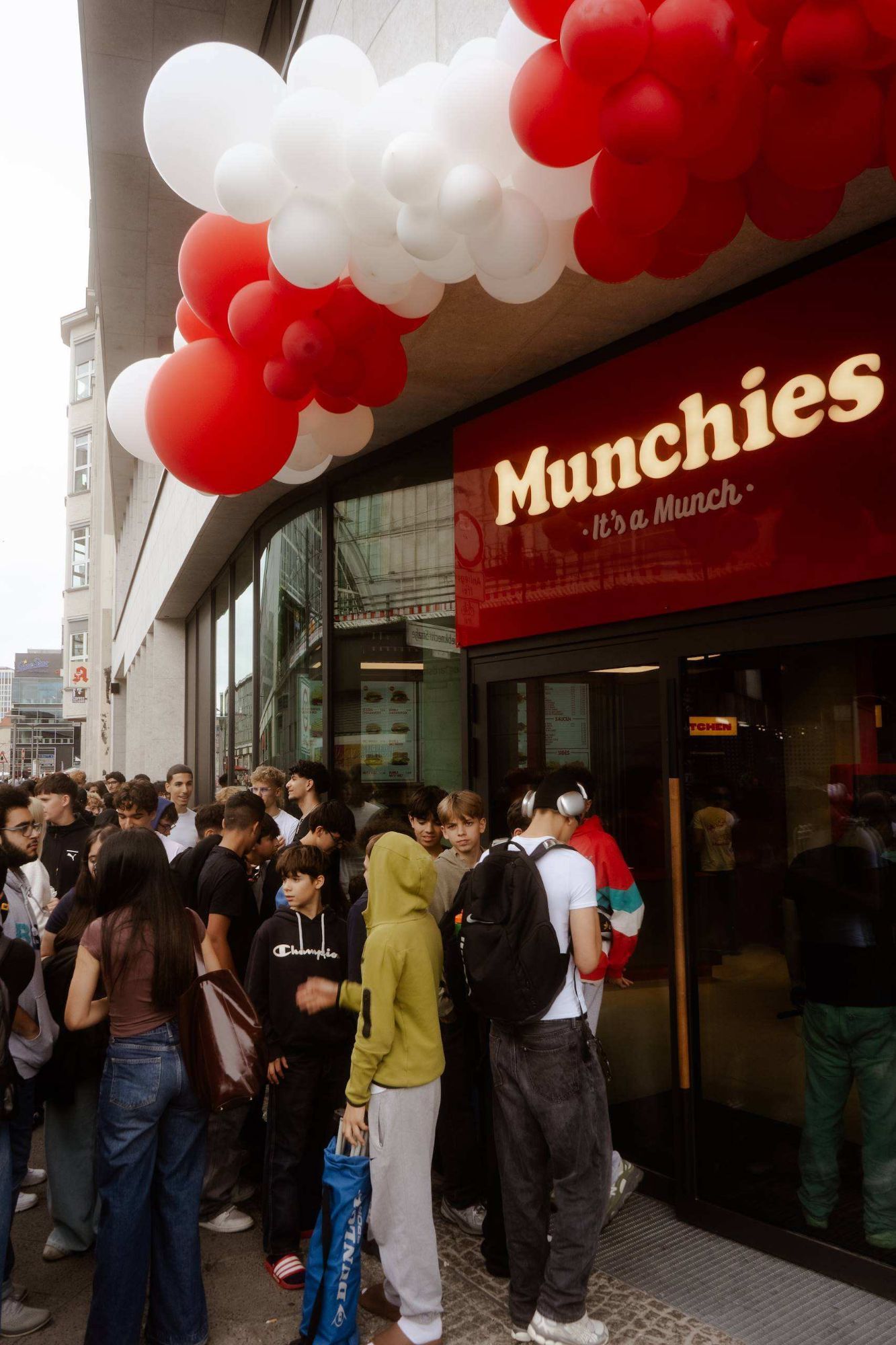 Eingang des Munchies Stores am Alexanderplatz mit leuchtendem Schriftzug und Ballonbogen