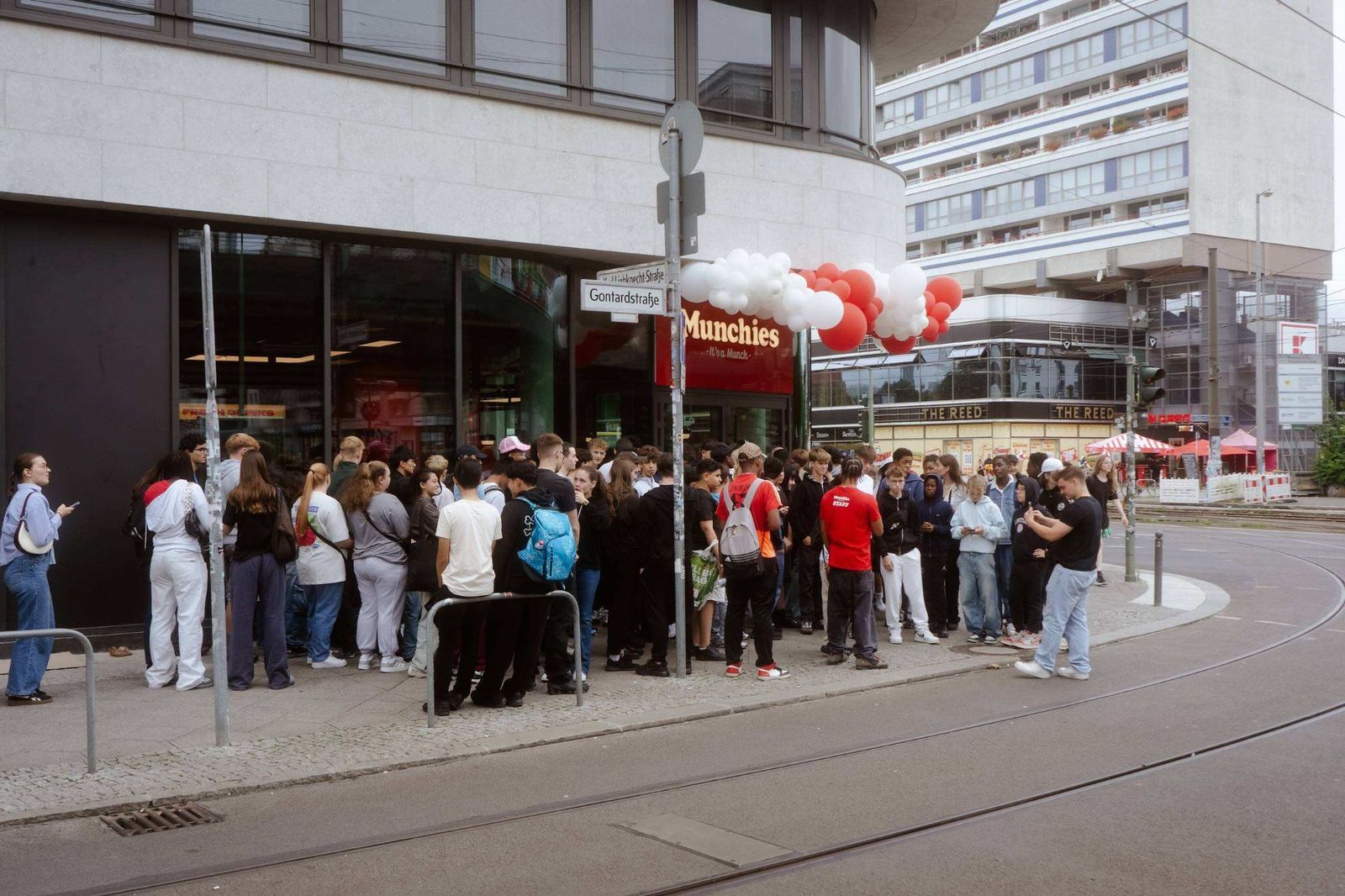 Menschenmenge vor dem neuen Munchies Store am Alexanderplatz, darüber ein Ballonbogen in Rot und Weiß