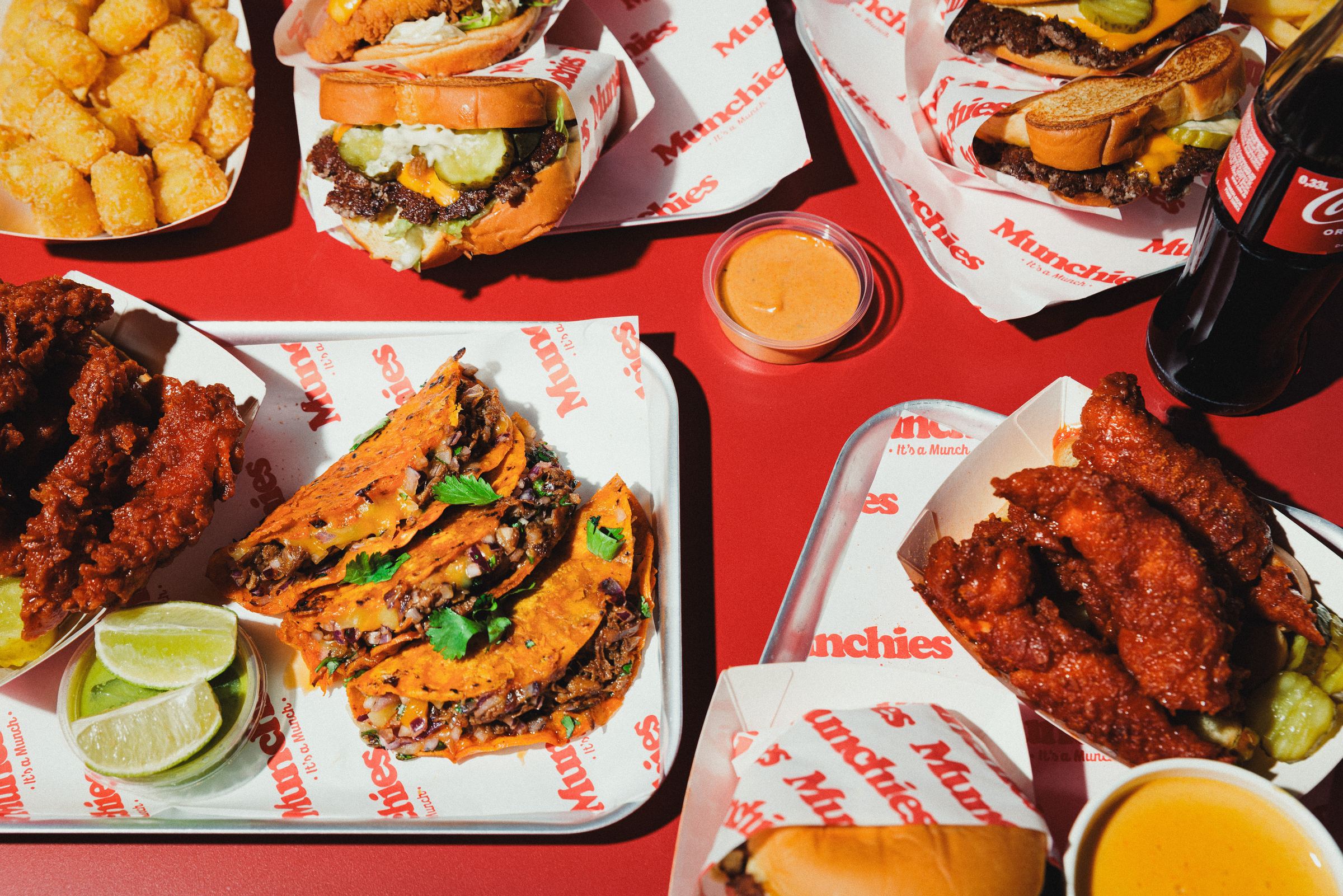 Smash Burger, Birria Tacos, Crispy Chicken und Tater Tots auf rotem Tisch